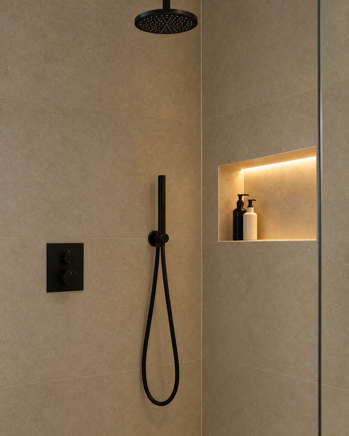 Illuminated shower niche beside a matt black thermostatic control and handset